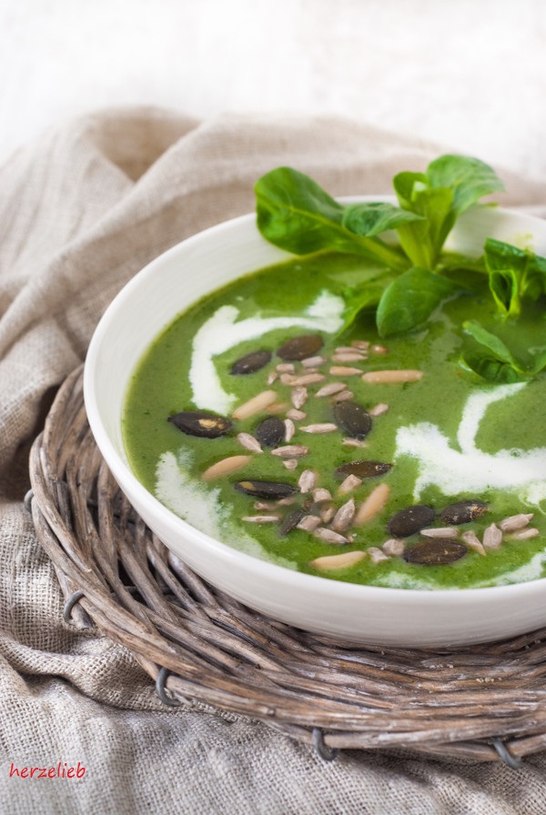 Dieses Foto zum Brokkolisuppe Rezept zeigt einen Teller der tiefgrünen Suppe, dekoriert mit Saaten und einem Büschel Feldsalat