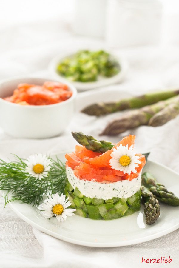 Spargel-Salat, geschichtet auf einem Teller angerichtet. Mit Spargel-Spitzen und Gänseblümchen