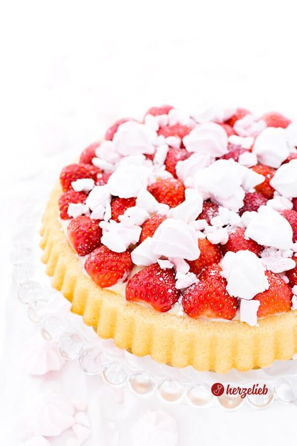 Schneller Erdbeerkuchen nach einem Obstboden Rezept mit Pudding und Erdbeeren von herzelieb. Die Erdbeertorte ist dekoriert mit Baiserkrümeln.