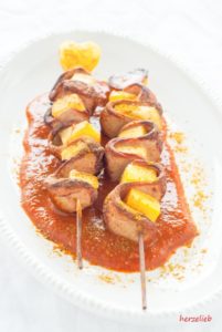 Zwei knusprige Currywurst-Sticks auf einem weißen Teller mit selbstgemachter Currysoße