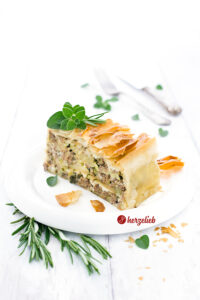 Ein Stück Hack-Zucchini-Lasagne mit Feta im Filoteig nach einem Rezept von herzelieb. Dekoriert mit Oregano und Rosmarin
