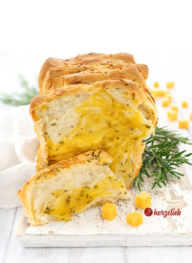 Käse-Zupfbrot Rezept mit Kräutern. Mit Käsewürfeln und Rosmarin dekoriert.