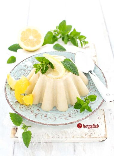 Ein türkisfarbenen Teller mit Pudding wie von Oma, dekoriert mit Zitronenmelisse und Zitronenschale. Nach dem Zitronenpudding Rezept unserer Oma.
