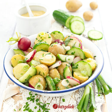 Eine Schale mit Pellkartoffelsalat aus Dänemark sieh man auf diesem Bild zum dänischer Kartoffelsalat Rezept von herzelieb. Er ist zubereitet mit Pellkartoffeln, Gurken, Radieschen, Schnittlauch und einem Senfdressing