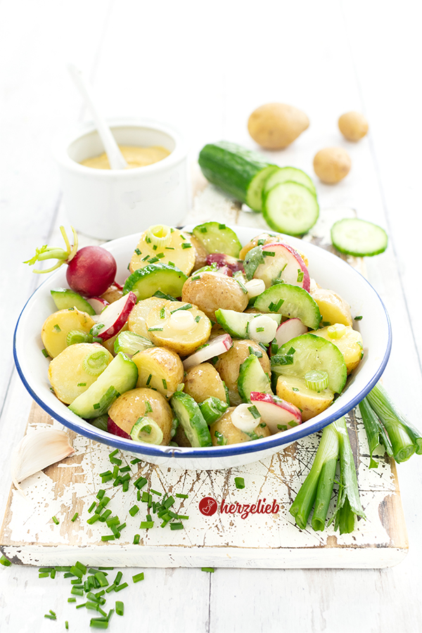 Eine Schale mit Pellkartoffelsalat aus Dänemark sieh man auf diesem Bild zum dänischer Kartoffelsalat Rezept von herzelieb. Er ist zubereitet mit Pellkartoffeln, Gurken, Radieschen, Schnittlauch und einem Senfdressing