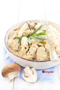 Eine schräg von oben fotografierte Geflügelpfanne mit Pilzen nach dem Senf-Hähnchenpfanne Rezept von herzelieb