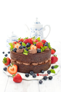 Djævlekage mit Schokoladencreme, Erdbeeren und Blaubeeren nach einem Teufelskuchen oder Teufelstorte Rezept von herzelieb von vorne fotografiert.