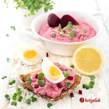 Rote Bete Meerrettich Aufstrich auf Schwarzbrot. Dekoriert mit Kresse, kleinen Rotete Bete Würfeln und Ei. Im Hintergrund eine halbe Zitrone, ein halbes Ei . Ganz hinten eine Schale mit dem Dip bzw. dem Brotaufstrich und ein Büschel Brunnenkresse