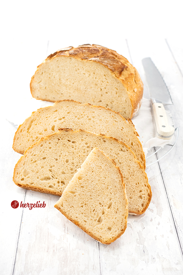 Ein aufgeschnittenes Topfbrot oder Dinkelbrot nach einem Dinkel-Joghurt-Brot Rezept von herzelieb. Im Hintergrund rechts ein Brotmesser.