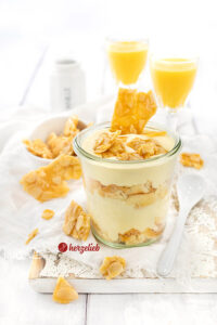 Ein Weckglas mit einem Schichtdessert nach einem Bienenstich-Eierlikör Rezept von herzelieb. Dekoriert mit selbsgemachtem Mandelkrokant.