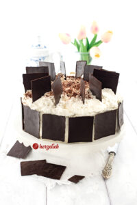 Eine kleine Torte miit Sahne und Schokotäfelchen nach einem Schwarzwaldtårta Rezept aus Schweden auf einem weißen Tortenteller angerichtet