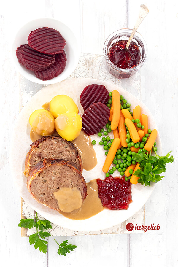 2 Scheiben falscher Hase oder aus Dänemark nach einem Forloren Hare Rezept von herzelieb.Angerichtet ist der Hackbraten mit  Kartoffeln, Soße, Rote Bete, roter Johannisbeermarmelade und Erbsen mit Möhren. Umwickelt ist er mit Bacon.