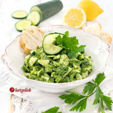 Kohlsalat oder Gurkensalat mit einem grünen Dressing nach einen Grüne Göttin Salat Rezept von herzelieb. Dekoriert mit Gurkenscheiben und glatter Petersilie. Im Hintergrund eine halbe und eine ganze