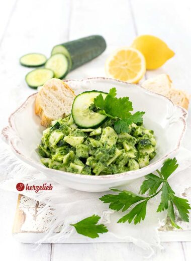 Kohlsalat oder Gurkensalat mit einem grünen Dressing nach einen Grüne Göttin Salat Rezept von herzelieb. Dekoriert mit Gurkenscheiben und glatter Petersilie. Im Hintergrund eine halbe und eine ganze