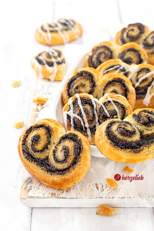 Eine Schale mit Gebäckschneckend nach einem Mohnschnecken Rezept von herzelieb. Die Schnecken sind goldbraun gebacken und einige sind mit Zuckerguss verziert.