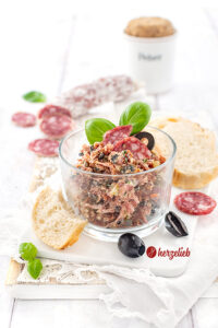 Rustami Aufstrich nach einem Salami-Brotaufstrich Rezept von herzelieb. Angerichtet mit Brot, Salamischeiben, Oliven und Basilikum.