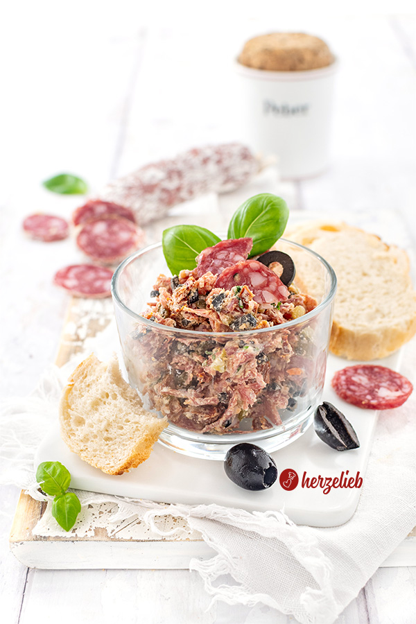 Rustami Aufstrich nach einem Salami-Brotaufstrich Rezept von herzelieb. Angerichtet mit Brot, Salamischeiben, Oliven und Basilikum.