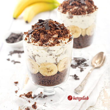 Ein Nachtisch nach einem Maulwurfkuchen Dessert im Glas mit Schokokuchen, Bananenscheiben, Sahnecreme und Schokoraspeln, dekorativ geschichtet und mit Schokoraspeln bestreut.