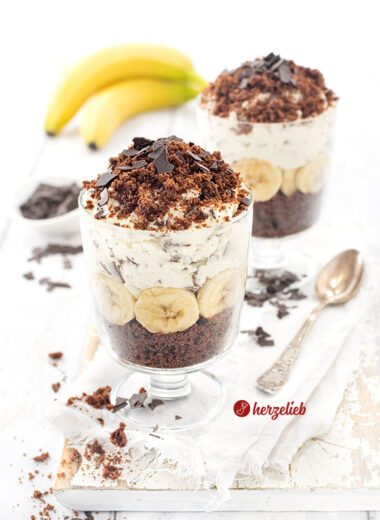 Ein Nachtisch nach einem Maulwurfkuchen Dessert im Glas mit Schokokuchen, Bananenscheiben, Sahnecreme und Schokoraspeln, dekorativ geschichtet und mit Schokoraspeln bestreut.