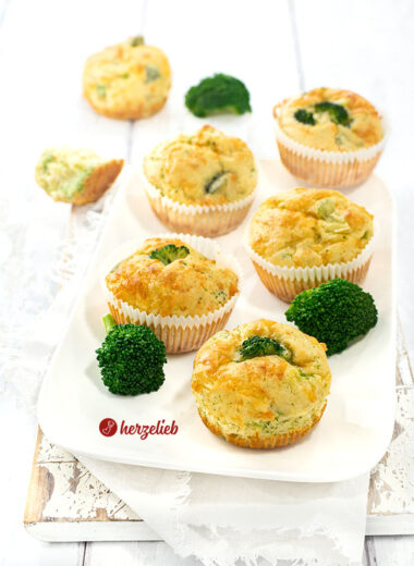 6 herzhafte Muffins nach einem Brokkoli-Käse-Muffins Rezept von herzelieb auf einem weißen Teller. Dekoriert mit Brokkoliröschen.