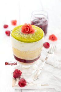 Ein Schichtdessert mit grünem Marzipandeckel mit einer Rose, der mit Puderzucker bestäubt und aus 5 weiteren Schichten besteht, nach einem Prinsesstårta Dessert im Glas Rezept von herzelieb. Die Prinzessinnentorte aus Schweden als Nachtisch.