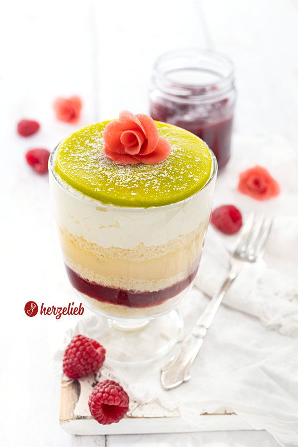Ein Schichtdessert mit grünem Marzipandeckel mit einer Rose, der mit Puderzucker bestäubt und aus 5 weiteren Schichten besteht, nach einem Prinsesstårta Dessert im Glas Rezept von herzelieb. Die Prinzessinnentorte aus Schweden als Nachtisch.