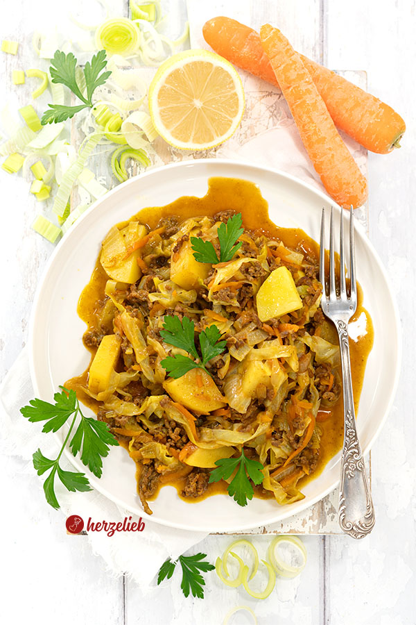 Indianergryde mit Kartoffeln, Weißkohl, Karotten und Lauch aus Dänemark auf einem weißen Teller