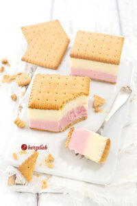 Joghurt-Wackel-Kuchen mit einer roten und einee weißen Schicht aus Joghurt. Am Boden und obenauf Butterkekse