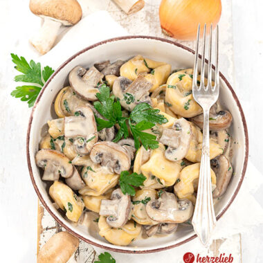 Eine Schale mit einem Pastagericht nach einem Pilz-Tortellini-Topf Rezept von herzelieb. In der Schüssel Tortellini, Pilze und eine helle Soße. Dekoriert mit Petersilie
