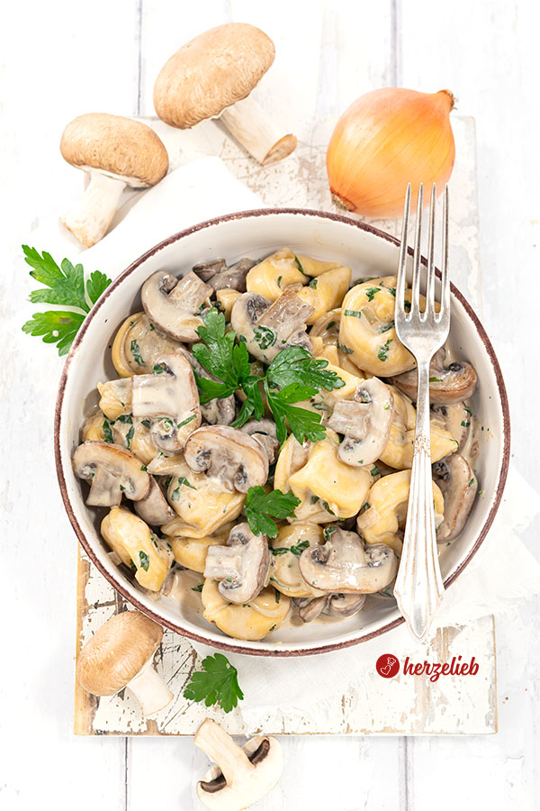 Eine Schale mit einem Pastagericht nach einem  Pilz-Tortellini-Topf Rezept von herzelieb. In der Schüssel Tortellini, Pilze und eine helle Soße. Dekoriert mit Petersilie