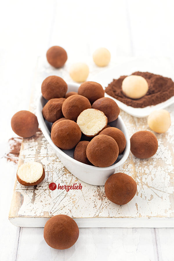 Kleine Marzipankugeln, die mit Kakao umhüllt sind nach einem Falsche Marzipankartoffeln Rezept von herzelieb. Angerichtet in einer länglichen, ovalen, weißen Porzellanschale.