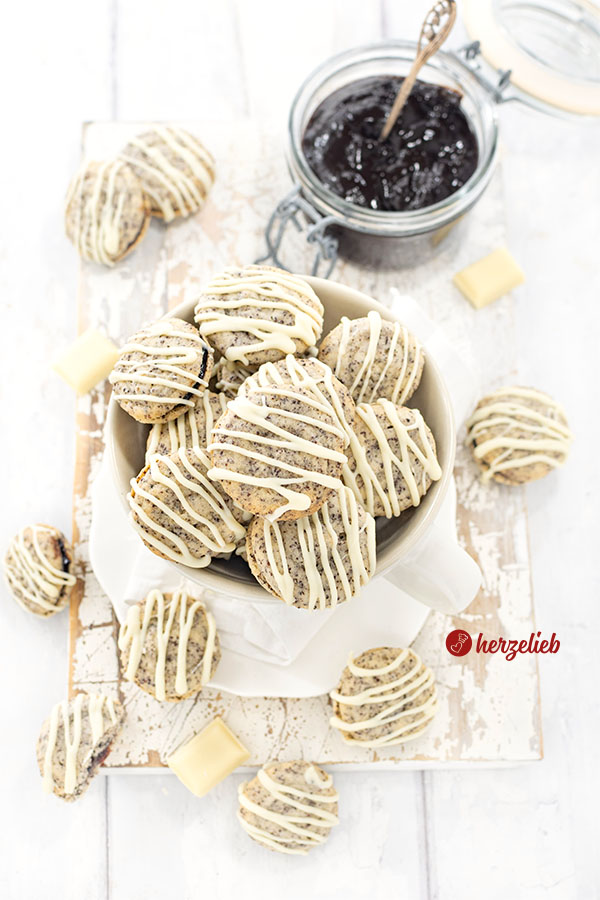 Mit Pflaumenmus gefüllte Mohnplätzchen nach einem Germknödel Plätzchen Rezept von herzelieb. Die Kekse sind mit weißer Kuvertüre verziert. 