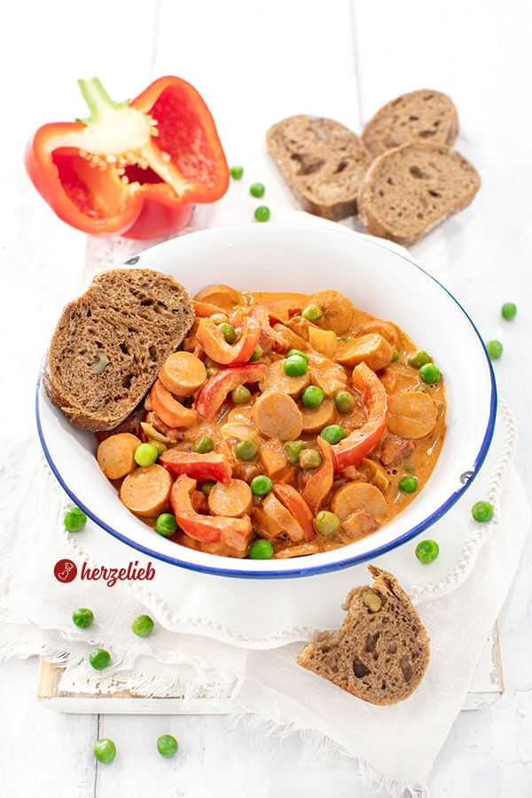 Schneller Würstcheneintopf nach einem Piratgryde Rezept von herzelieb. Angerichtet mit Brot - im Eintopf Paprikastücke, Erbsen und Würstchenscheiben zu sehen.