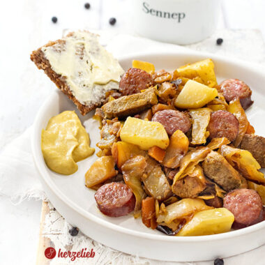 Ein Teller mit Kohleintopf nach einem Sømandskål Rezept aus Dänemark. Im Gericht sieht man Kartoffeln, Kohlwurst, Filtestücke, Weißkohl und Möhren