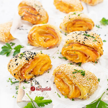 Neun, mit Käse und Schinken gefüllte Blätterteigteilchen nach einem Blätterteigschnitten Rezept von herzelieb. Dekoriert mit Petersilie.