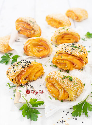 Neun, mit Käse und Schinken gefüllte Blätterteigteilchen nach einem Blätterteigschnitten Rezept von herzelieb. Dekoriert mit Petersilie.