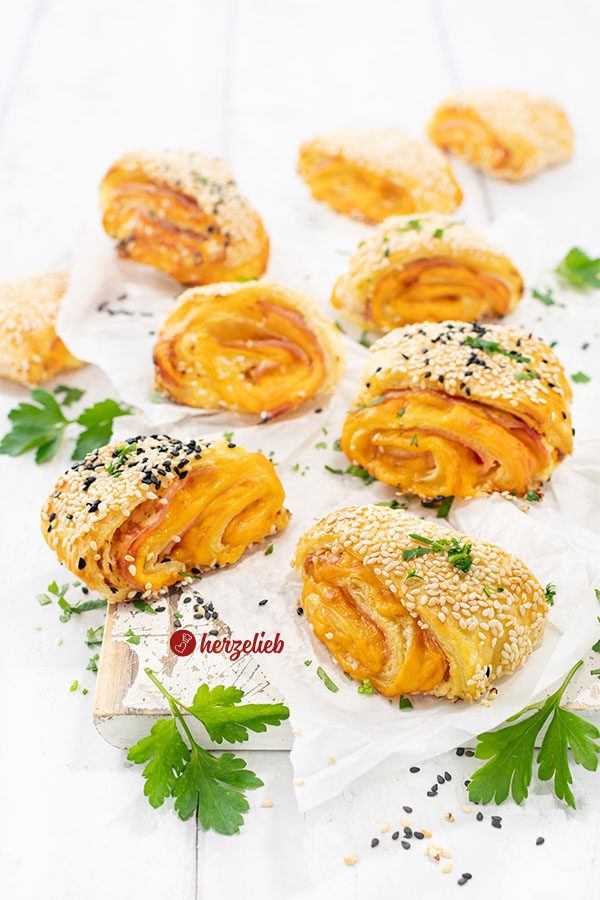Neun, mit Käse und Schinken gefüllte Blätterteigteilchen nach einem Blätterteigschnitten Rezept von herzelieb. Dekoriert mit Petersilie.