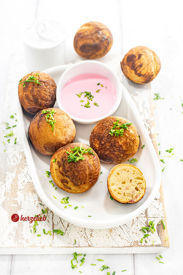 Goldbraun gebackene Gebäckbällchen nach einem herzhafte Æbleskiver Rezept aus Dänemark von herzelieb. Die Förtchen sind bestreut mit gehacktem Schnittlauch und sind mit einem Rote Bete Frischkäse serviert