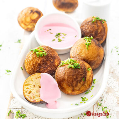 Kleine Gebäckbällchen nach einen herzhafte Æbleskiver Rezept aus Dänemark von herzelieb. Angerichtet auf einer ovalen Porzellanplatte, serviert mit einem Rote Bete Frischkäse und dekoriert mit gehacktem Schnittlauch