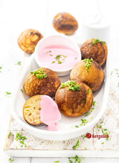Kleine Gebäckbällchen nach einen herzhafte Æbleskiver Rezept aus Dänemark von herzelieb. Angerichtet auf einer ovalen Porzellanplatte, serviert mit einem Rote Bete Frischkäse und dekoriert mit gehacktem Schnittlauch