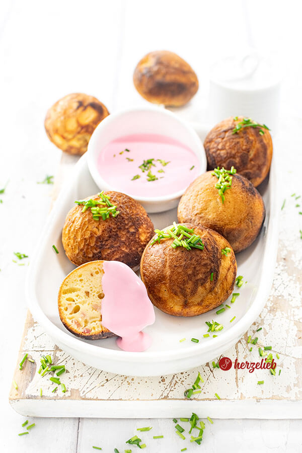 Kleine Gebäckbällchen nach einen herzhafte Æbleskiver Rezept aus Dänemark von herzelieb. Angerichtet auf einer ovalen Porzellanplatte, serviert mit einem Rote Bete Frischkäse und dekoriert mit gehacktem Schnittlauch