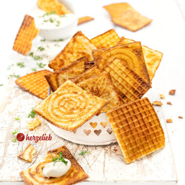 Dünne, knusprige und goldbraune Waffeln nach einem Käsewaffeln Rezept für das Zimtwaffeleisen. Angerichtet in einer kleine, weißes Schale. Im Hintergrund ein Schälchen Dip. Dekoriert mit Kresse.