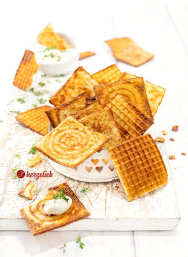 Dünne, knusprige und goldbraune Waffeln nach einem Käsewaffeln Rezept für das Zimtwaffeleisen. Angerichtet in einer kleine, weißes Schale. Im Hintergrund ein Schälchen Dip. Dekoriert mit Kresse.