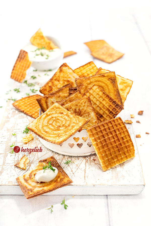 Dünne, knusprige und goldbraune Waffeln nach einem Käsewaffeln Rezept für das Zimtwaffeleisen. Angerichtet in einer kleine, weißes Schale. Im Hintergrund ein Schälchen Dip. Dekoriert mit Kresse.