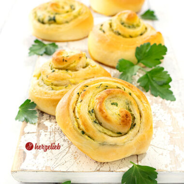 5 herzhafte Hefeschnecken nach einem Kartoffelschnecken Rezept von herzelieb auf einem weißen Brett. Saftig, zartgebräunt, dekoriert mit glatter Petersilie.