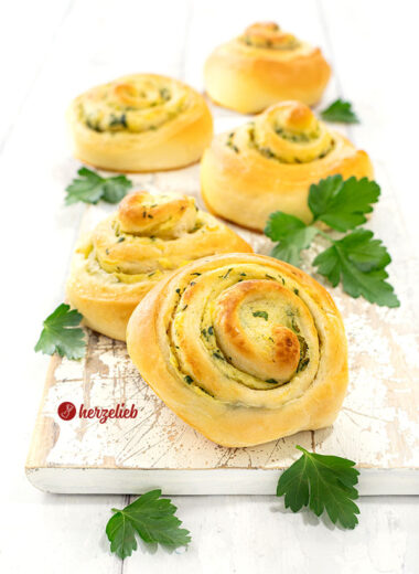 5 herzhafte Hefeschnecken nach einem Kartoffelschnecken Rezept von herzelieb auf einem weißen Brett. Saftig, zartgebräunt, dekoriert mit glatter Petersilie.