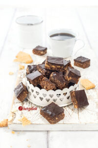 Eine Kleine Metallschale mit kleinen, knusprigen Schokohappen. Die Miniwürfel haben einen Schokoguss.