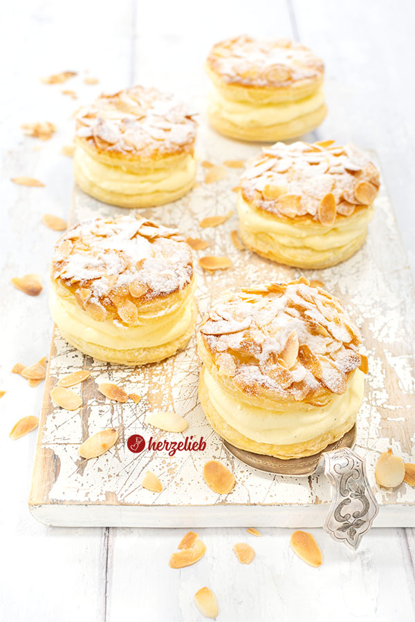 5 Bienenstichtörtchen aus Blätterteig.Obenauf Mandeln und Puderzucker. 