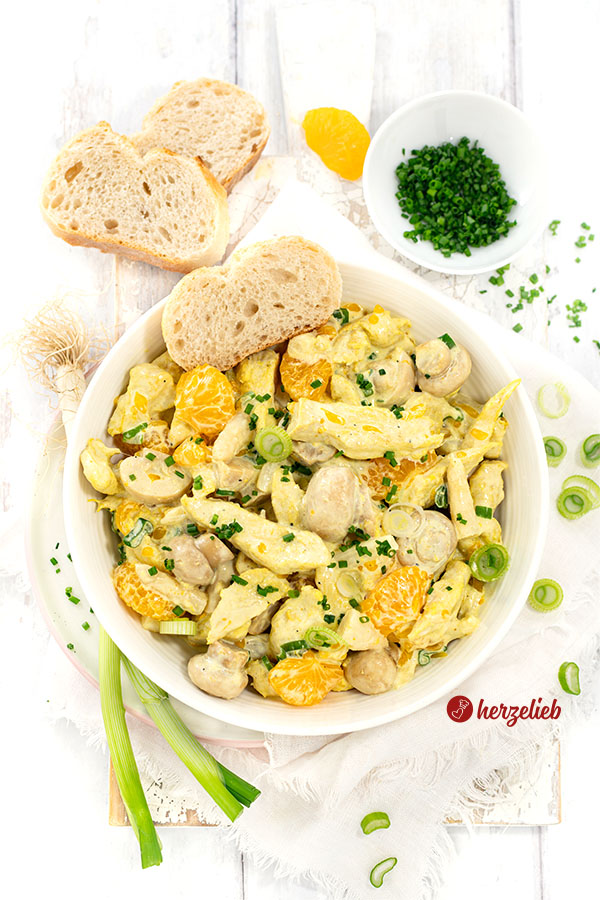 Von oben eine weiße Schale mit Geflügelsalat wie von Oma. Im Salat außerdem: Spargel und Pilze. Angerichtet mit Brot. Dekoriert mit Frühlingszwiebeln.