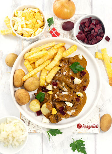 Kong Fiddes Livret mit Pommes und Kartoffeln auf einem Teller angerichtet. Serviert mit Ei, Rote Bete und Zwiebeln. Dekoriert mit Petersilie.